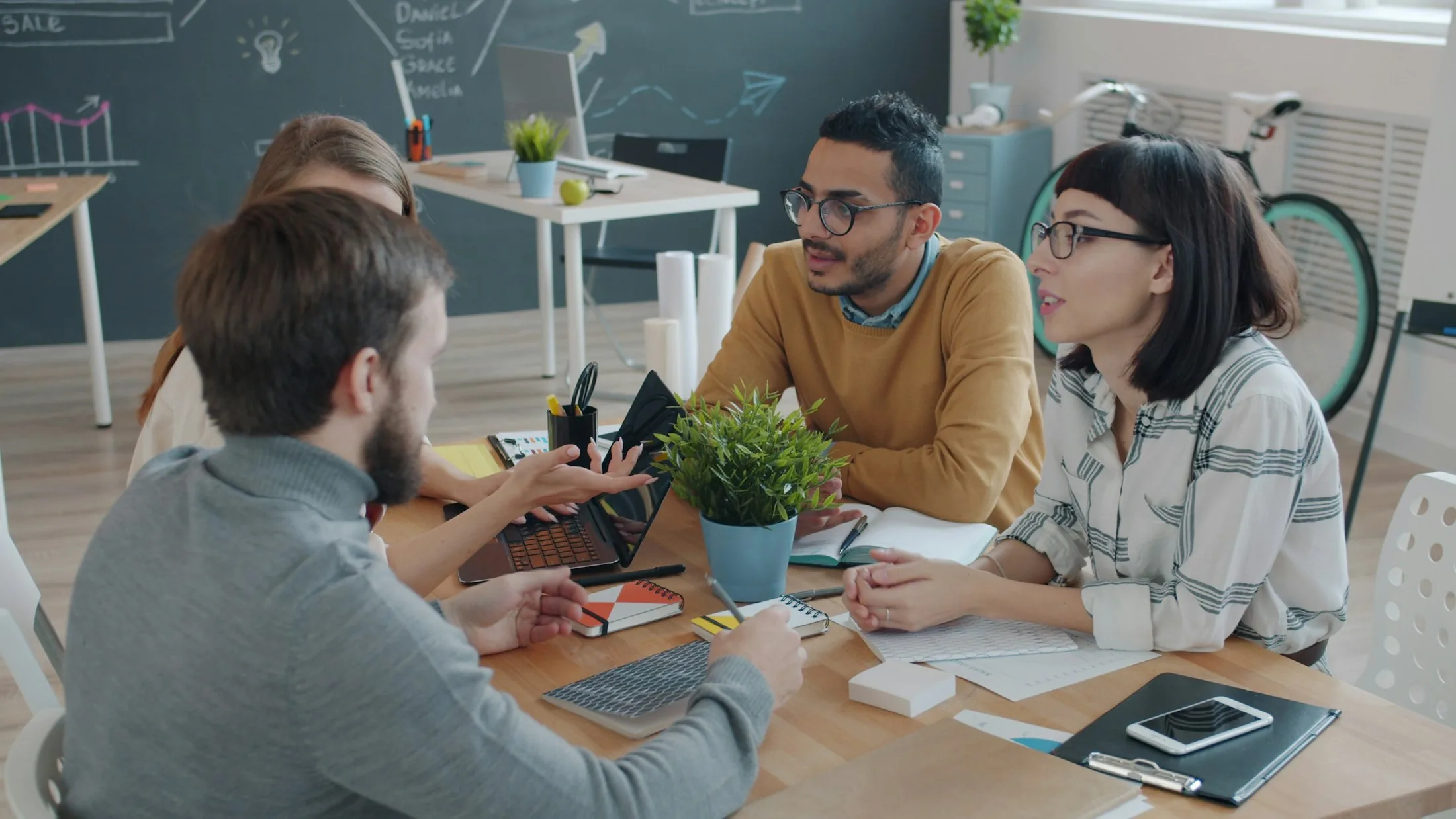 A diverse team high-fiving and laughing around a table during a staff meeting