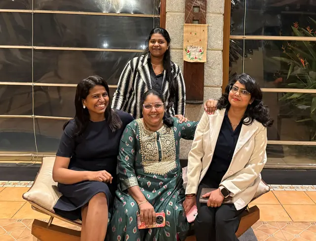 Four colleagues posing together on a wooden bench at the awards evening
