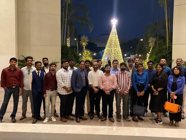 The team in front of a tall tree strung with lights, at night