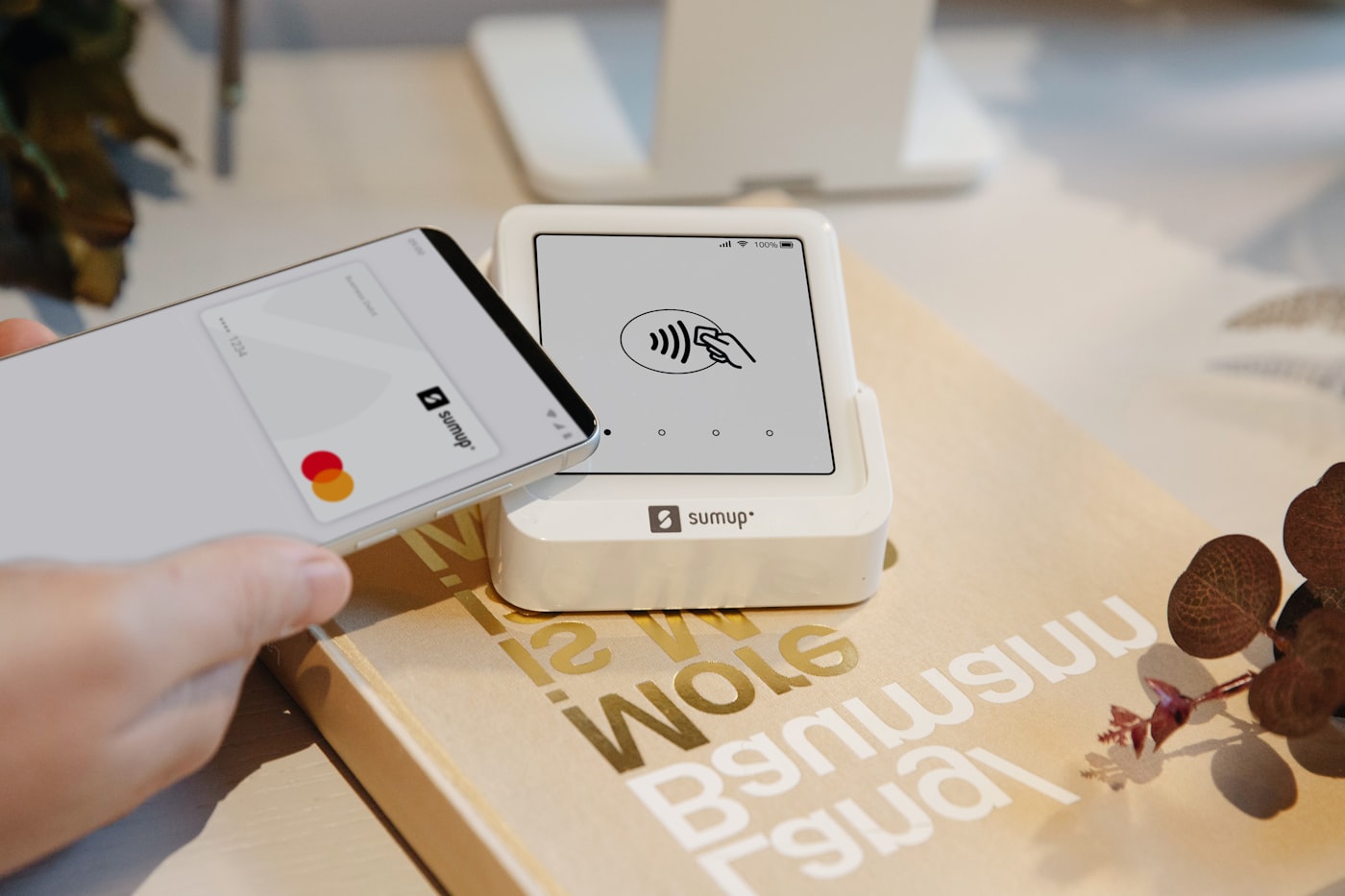 A smartphone tapped against a card reader to complete a contactless payment