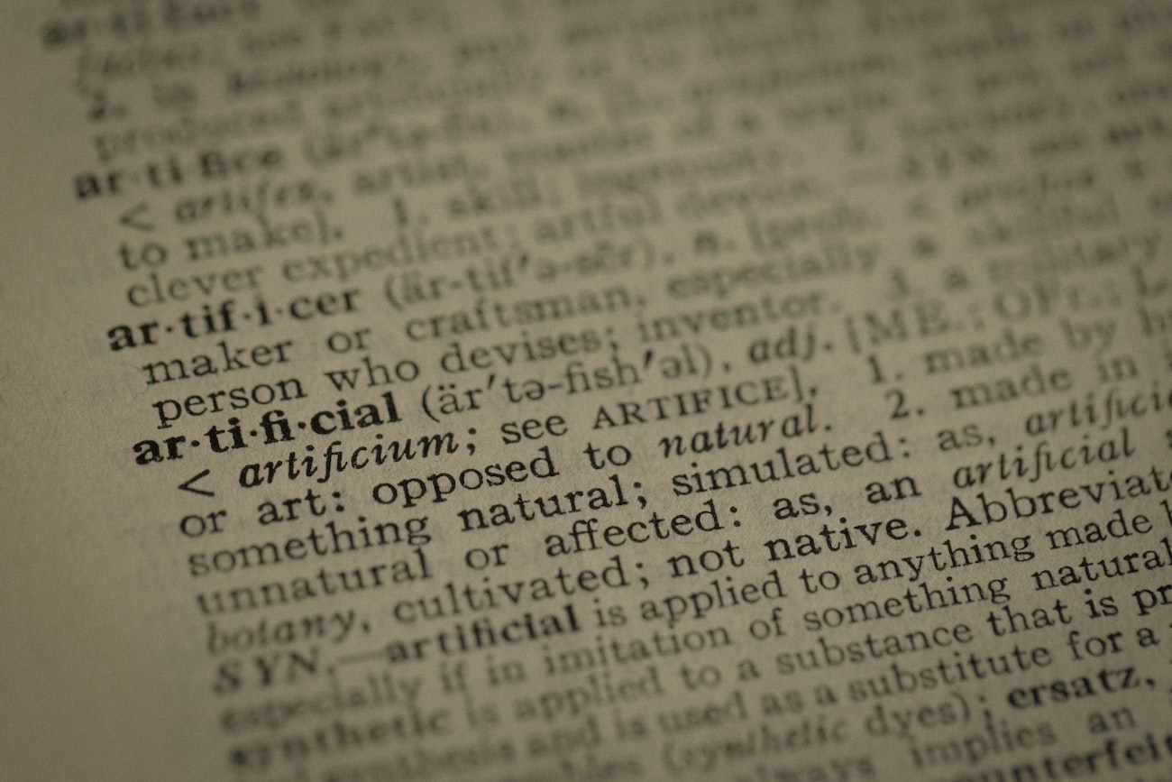 Close-up of a printed dictionary page, open at the entry for the word artificial