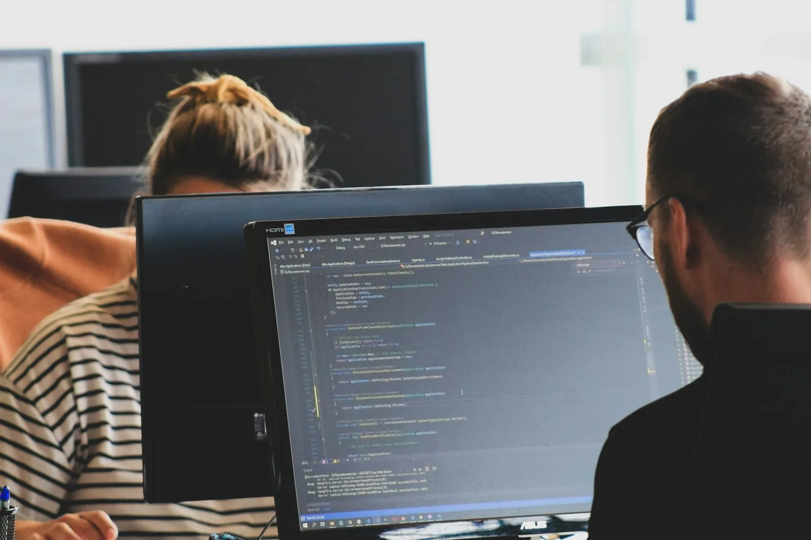 Two engineers reviewing code together on a monitor